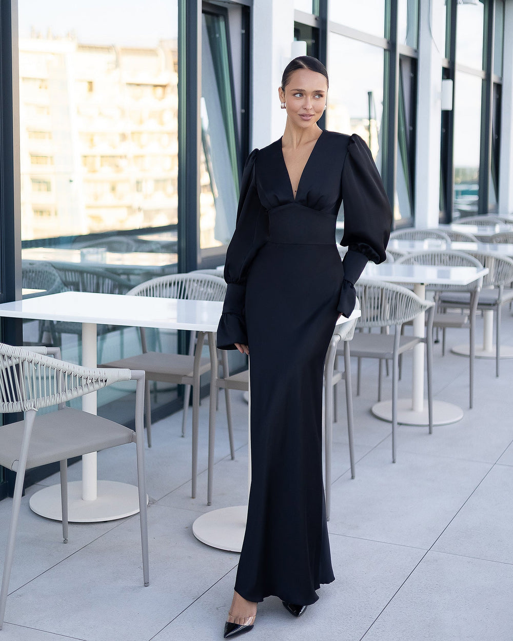 Woman in a long, elegant dress standing on a balcony with ocean view