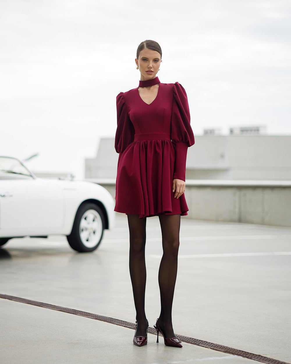 Woman in a black dress sitting on a white car with a scenic background